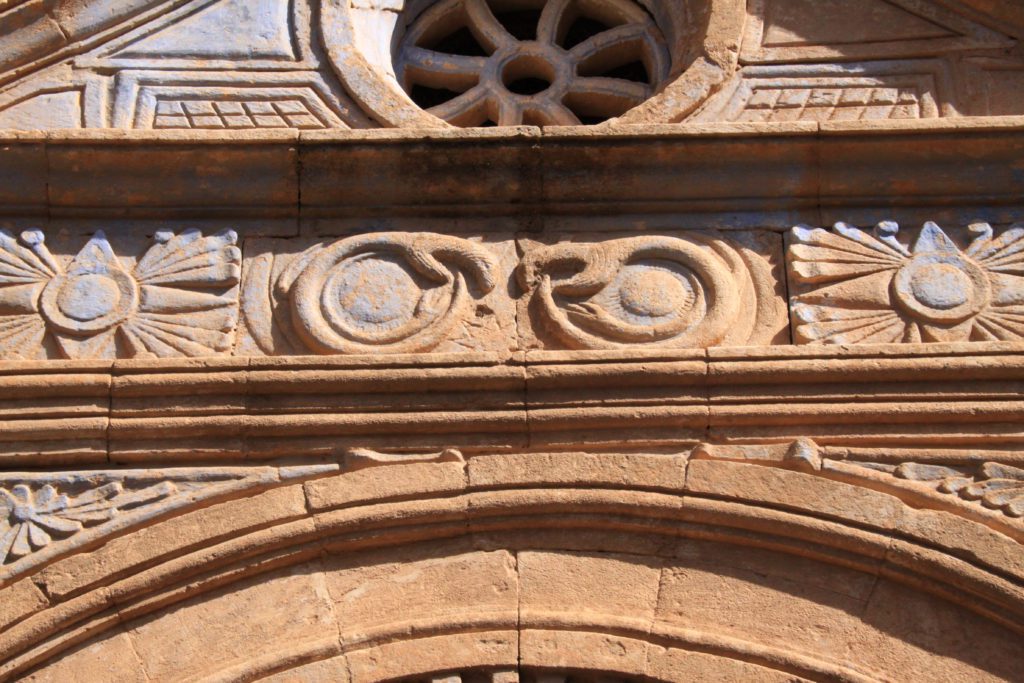 two symbols of tail eating snake ouroboros on the front of a church