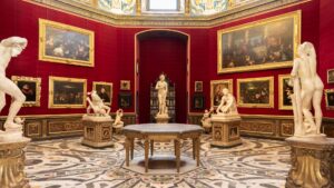 art museum room with red walls, paintings and sculptures