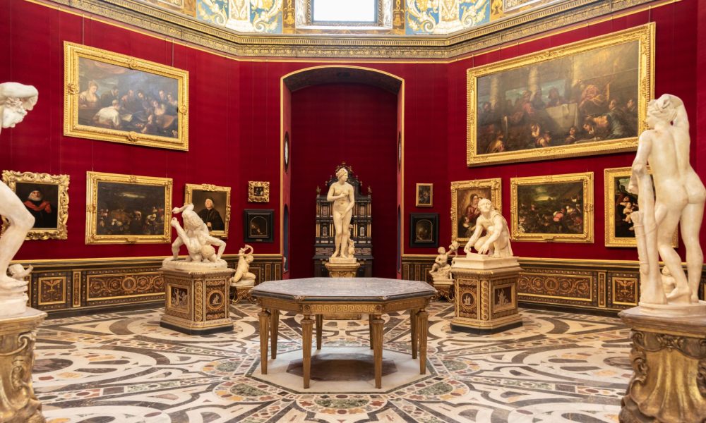 art museum room with red walls, paintings and sculptures